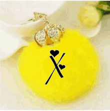 a yellow keychain with the letter x and hearts on it