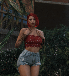 a woman with red hair wearing a red polka dot top and shorts