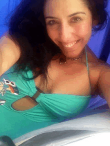 a woman in a blue swimsuit is smiling and wearing a necklace