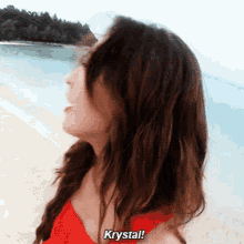 a woman standing on a beach with krystal written on her shirt