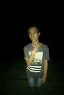 a young man wearing a new york t-shirt is giving a peace sign