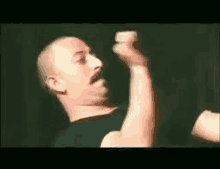 a man with a mustache is flexing his muscles in a dark room .