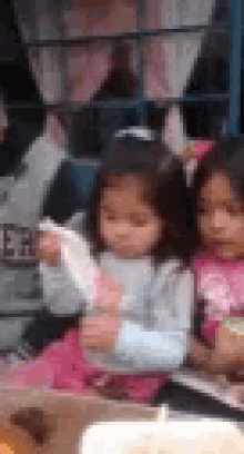 a group of little girls are sitting at a table eating food . one of the girls is holding a piece of paper .