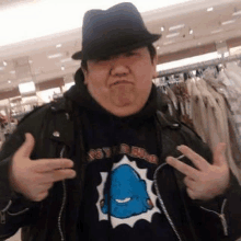 a fat man wearing a hat and a hoodie is making a funny face while standing in a store .