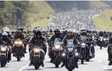 a large group of motorcycle riders are riding down a road