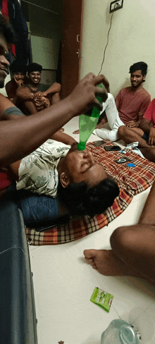 a group of young men are sitting on the floor and one of them is drinking from a bottle