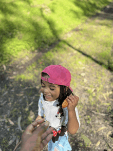 a little girl wearing a pink hat is holding a donut in her hand