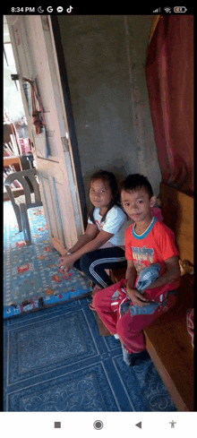 a boy and a girl are sitting on a bench in a room