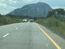 a road with a mountain in the background and cars driving on it