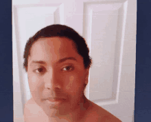 a woman without a shirt is taking a selfie in front of a white door