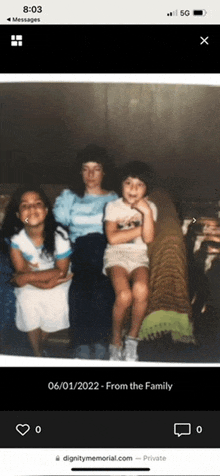 a phone screen shows a picture of three young girls sitting on a bed