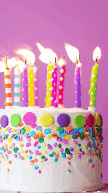 a birthday cake with lit candles and sprinkles on it