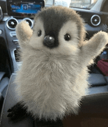 a stuffed penguin is sitting in a car with its arms outstretched