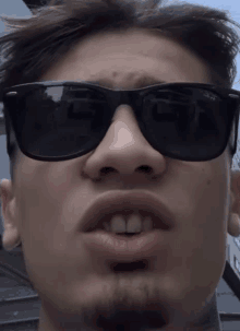 a close up of a man wearing sunglasses and making a silly face