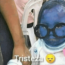 a little girl with blue paint on her face and glasses is holding someone 's hand .