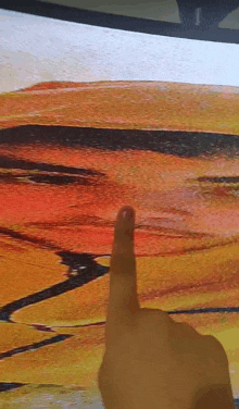 a person 's finger is pointing at a painting of a man 's face