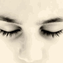 a close up of a woman 's face with her eyes closed and long eyelashes .