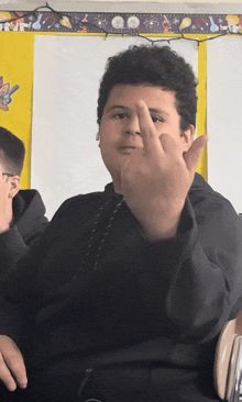 a man giving the middle finger in front of a bulletin board that says time