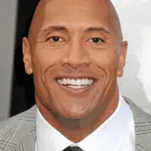 a bald man wearing a suit and tie is smiling .