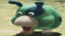 a green and blue cartoon character with a big nose and big eyes is walking on the ground .