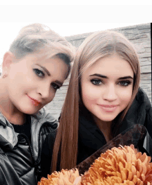 a woman and a girl are posing for a picture and the girl is holding a bouquet of flowers