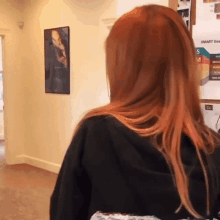 a woman with red hair is standing in front of a sign that says january 1