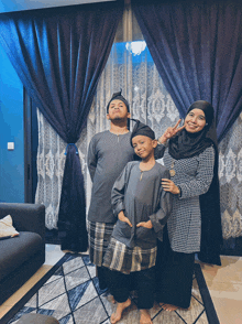 a woman and two children pose for a picture in front of a blue curtain