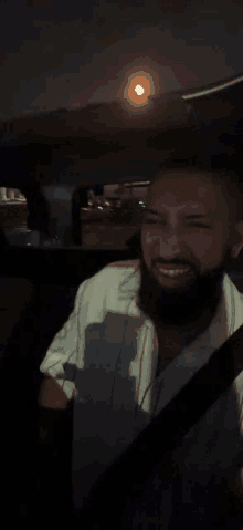 a man with a beard is smiling while sitting in a car at night