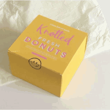 a box full of knotted fresh donuts sits on a piece of paper