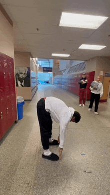 a man bending over in a hallway with a picture of einstein on the wall