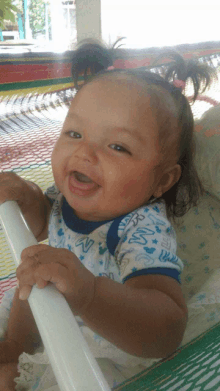 a baby wearing a mickey mouse shirt is sitting in a hammock