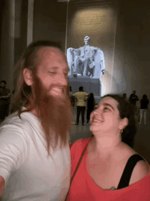 a man with a beard stands next to a woman in front of lincoln 's statue