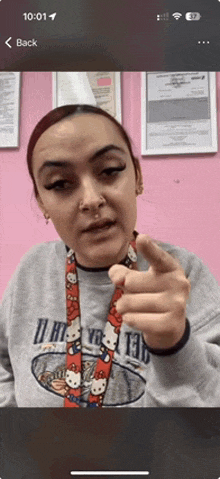 a woman wearing a hello kitty lanyard pointing her finger at the camera