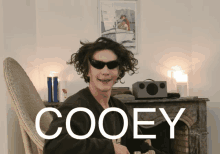 a young man wearing sunglasses sits in front of a fireplace with the name cooey written on the bottom