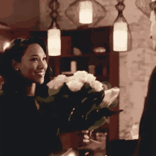 a woman is holding a bouquet of white roses