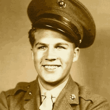 a young man in a military uniform and hat is smiling .