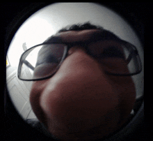 a man wearing glasses takes a fisheye photo of himself