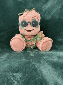 a stuffed animal wearing sunglasses and a necklace holds a glass