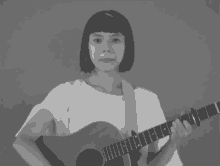 a woman in a white shirt is holding a guitar