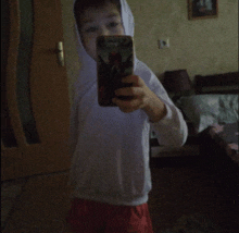 a young boy taking a selfie with a cell phone