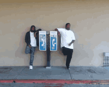 two men standing next to a phone booth that says ' phone ' on it