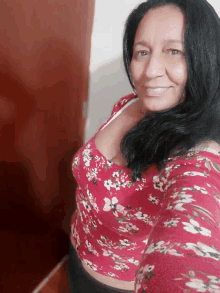 a woman in a red floral top smiles for a picture