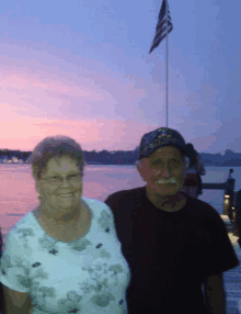 a man in a navy hat stands next to a woman on a dock