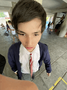 a young boy in a school uniform is looking down at something