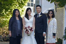 a bride and groom pose for a picture with their parents