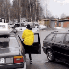 a man in a yellow jacket is getting out of a car with a hus ski sign on top of it