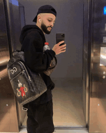 a man is taking a picture of himself in an elevator with a backpack that says dd on it