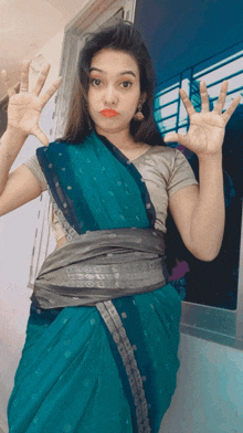 a woman in a blue saree is making a face with her hands