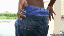 a man is standing in front of a chain link fence wearing blue shorts .