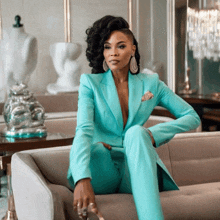 a woman in a teal suit sits on a couch